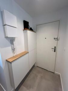 a white kitchen with a door and a cabinet at Studio face plage / centre ville in Arcachon