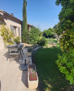 a garden with a table and a bench with flowers at LA MASTRONA in Saumane-de-Vaucluse