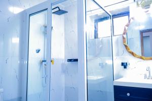 a white bathroom with a shower and a sink at The Stafford Lodge in Freetown +32 photos