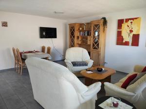 a living room with white chairs and a table at Ferienwohnung Blumenparadies in Nettersheim