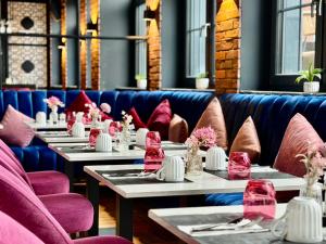 a row of tables in a restaurant with pink chairs at Twins Hotel in Duisburg