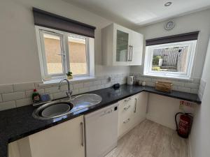 a small kitchen with a sink and two windows at Little Newlyn in Newlyn