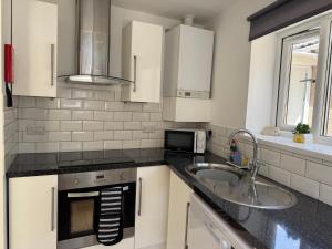 a kitchen with white cabinets and a sink and a microwave at Little Newlyn in Newlyn