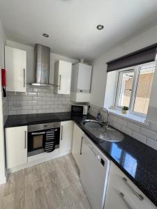 a kitchen with white cabinets and a sink at Little Newlyn in Newlyn