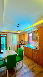 a kitchen with a table and green chairs at Badul Pansiyon in Uzungöl