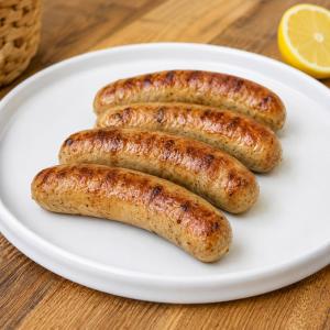 three sausages on a white plate on a table at Hotel Indrawoti and Resort in Dhulikhel