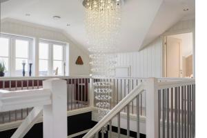 a room with a staircase with a chandelier at Romslig hus med jacuzzi, spillrom og stor terrasse in Fredrikstad