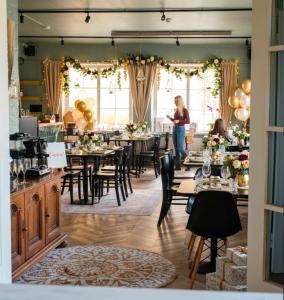 a woman standing in a room with tables and chairs at Villa Korsman in Hanko