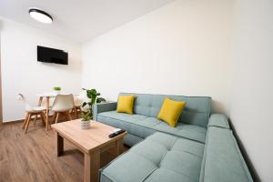 a living room with a blue couch and a table at Oropion Rental houses in Néa Palátia