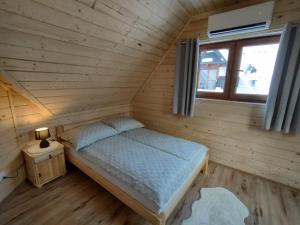 a bed in a wooden room with a window at Domki Pod Lasem Podhale in Zakopane