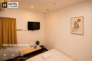 a room with a bed and a tv on the wall at H Hotel in Segamat