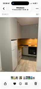 a kitchen with white cabinets and a white refrigerator at APARTAMENT PLUS in Włodawa