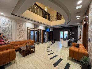 a lobby with orange furniture and a woman and a baby at Hotel Bella Vento Luxury Stay Near CGC Landran Mohali Chandigarh in Kharar