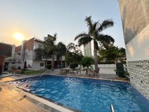 a large swimming pool with palm trees and a building at Hotel Bella Vento Luxury Stay Near CGC Landran Mohali Chandigarh in Kharar