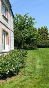 a house with a field of grass next to a building at Pušų Sodas in Birštonas