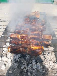 a bunch of ribs and bacon cooking on a grill at Green House -მწვანე სახლი in Tsalka