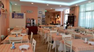 ein Restaurant mit weißen Tischen und weißen Stühlen und ein Zimmer in der Unterkunft Hotel Madrid in Cattolica