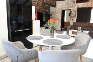 a white table and chairs with a vase of flowers on it at Kuća za odmor Leon in Vinkovci