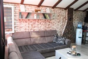a couch in a living room with a brick wall at Kuća za odmor Leon in Vinkovci