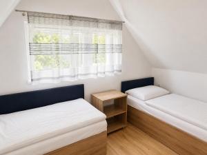 two beds in a small room with a window at Lubiatowe Love - domki w otulinie lasu in Lubiatowo