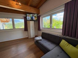 a living room with a couch and two windows at Ferienwohnung Heissl in Fieberbrunn