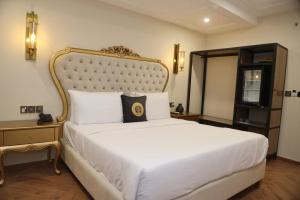 ein Schlafzimmer mit einem großen weißen Bett mit goldenem Rahmen in der Unterkunft Taj Signature Boutique Hotel Islamabad by LMY Hospitality in Islamabad