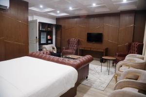 ein Zimmer mit Bett, Fernseher und Stühlen in der Unterkunft Taj Signature Boutique Hotel Islamabad by LMY Hospitality in Islamabad