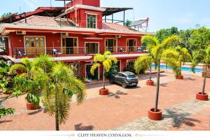 a red house with palm trees in front of it at Cliff Heaven in Colva