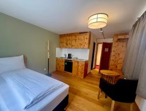 a bedroom with a bed and a kitchen with wooden cabinets at Hotel Alpenstadt in Chur