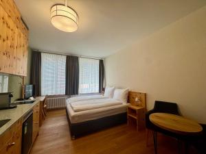 a room with a bed and a table and a kitchen at Hotel Alpenstadt in Chur