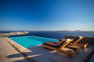a swimming pool with two lounge chairs and the ocean at Birdhouse Private Luxury Villa in Agios Ioannis Mykonos