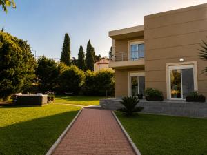 a house with a brick walkway in front of a yard at Phos & Kipos Villa in Koskinou