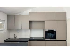a kitchen with white cabinets and a sink and a microwave at Apartments Antonela in Sveti Stefan