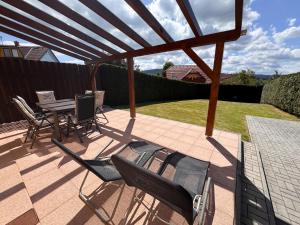 a patio with chairs and a table and a wooden pergola at Casa Maika in Frymburk
