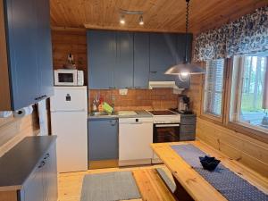 a kitchen with blue cabinets and a white refrigerator at Sininen Hetki Cottage in Kuusamo +31 photos