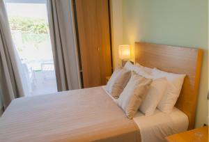 a bedroom with a bed with white pillows and a window at Hotel Novomar in Chiclana de la Frontera