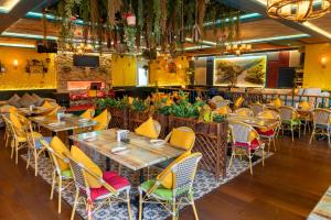 a restaurant with wooden tables and yellow chairs at Majestic Premier Hotel Burdubai in Dubai
