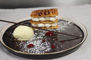 un piatto nero con un dolce con sopra il gelato di Logis Hotels Restaurants- Villa des Bordes a Cléry-Saint-André