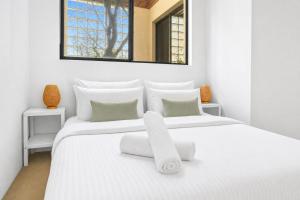 a white bedroom with a large white bed with white pillows at 2 Bedroom House Woolloomooloo in Sydney