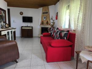 a living room with a red couch and a tv at Maria's House in Keramoti +11 photos