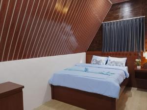 a bedroom with a bed with blue sheets at Galuh Hostel Lombok in Pawenang