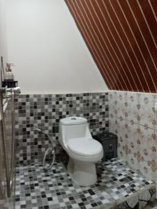 a bathroom with a toilet and a tiled floor at Galuh Hostel Lombok in Pawenang