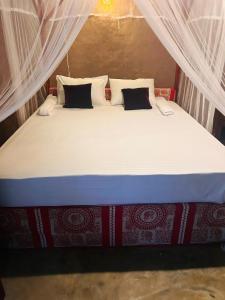 a large bed in a room with white curtains at AAA Happy Hostel in Arugam Bay