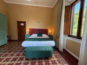 a bedroom with a bed and a green ottoman at Hotel Villa Porta All'Arco in Volterra