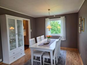 a dining room with a white table and chairs at Sjarmerende hus i havgapet i Selje in Salt