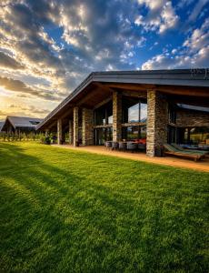 a building with a grass field in front of it at Hypnotic Thermal Villas with private SPA in Banya