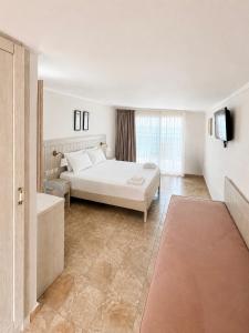 a white bedroom with a bed and a television at Myrto Rooms in Pefkochori +10 photos