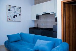 a blue couch in a living room with a kitchen at Dream Nest in Benin City