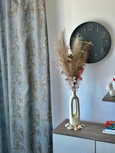 a vase on a table with a clock on a wall at SOLITA Apartment with Panoramic View in Byala