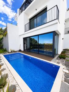 a villa with a swimming pool in front of a house at Villa Bavaria B in Ponta do Sol